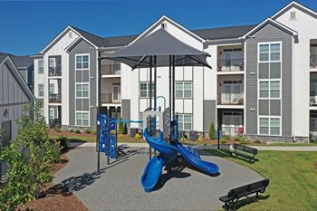 A playground with a blue slide in front of apartment buildings.
